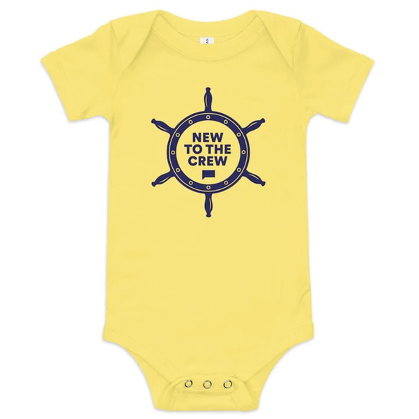 A Yellow baby onsie that reads "New to the Crew"