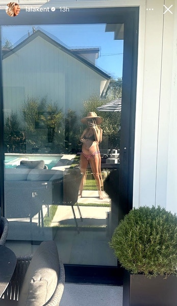 Lala Kent looking into a patio door at her reflection