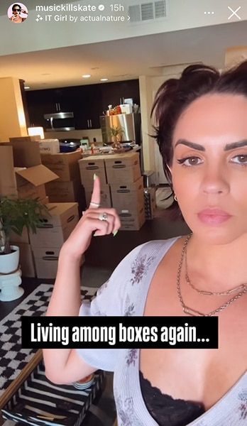 Katie Maloney standing in her apartment pointing to moving boxes.