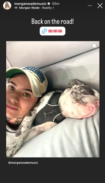 Morgan Wade wearing a baseball cap and laying on her dog, Chop.