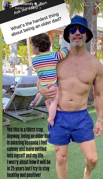 Andy Cohen holding his child outdoors.