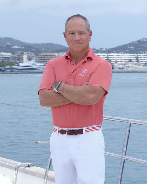 Captain Glenn Shephard posing in uniform onboard the Parsifal 3 in front of a marina.