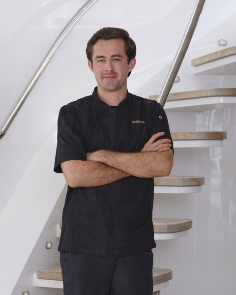 Cloyce Martin posing in uniform onboard the Parsifal 3 in front of a marina.