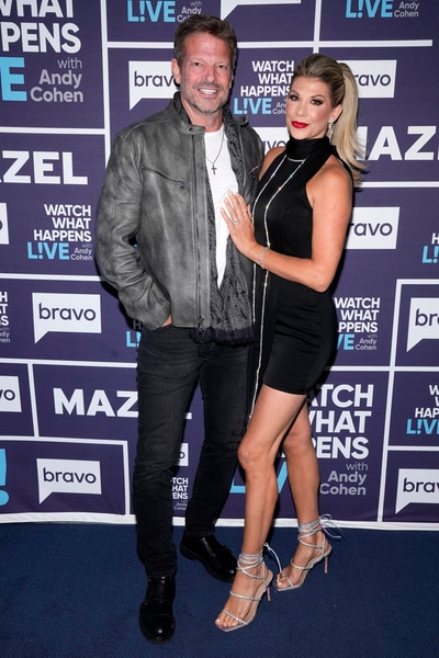 Alexis Bellino and her fiance John Janssen standing in front of the WWHL step and repeat