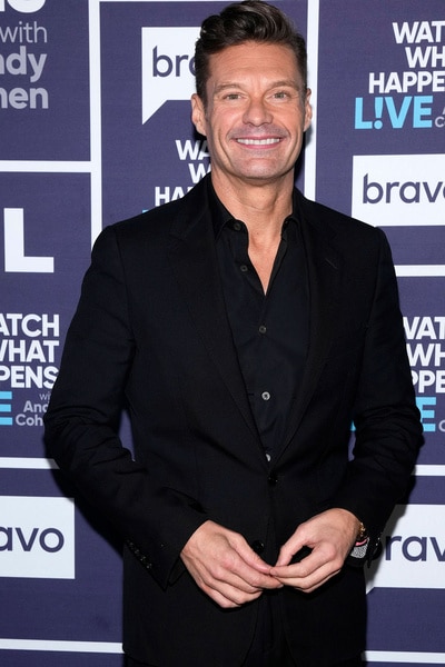 Ryan Seacrest posing in front of a step and repeat at Watch What Happens Live.