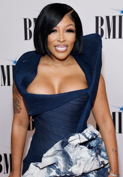 K Michelle smiling in front of a step and repeat.