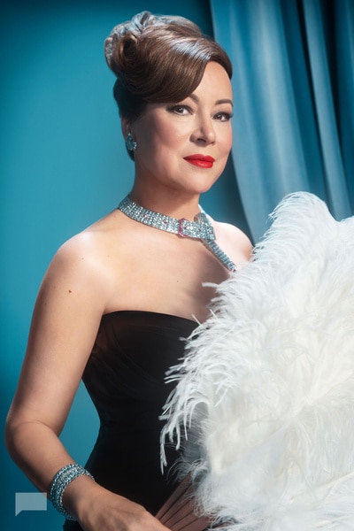 Jennifer Tilly while standing in front of a blue backdrop