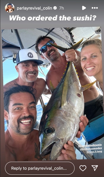 Colin Macrae posing on a boat with a fish in his hands with his friends.