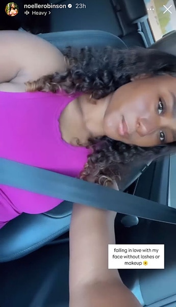 Noelle Robinson wearing a pink tank top and wearing curly hair while sitting in her car