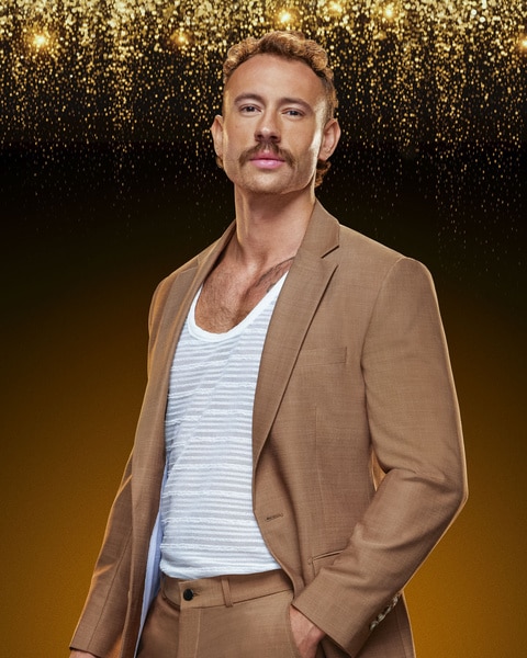 Austin Stephan wears a caramel suit in front of a backdrop in Southern Hospitality Season 3.