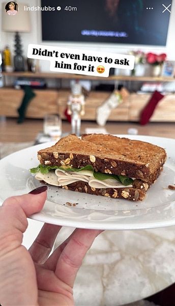 Lindsay Hubbard's hand holding a plate with a sandwich on it.