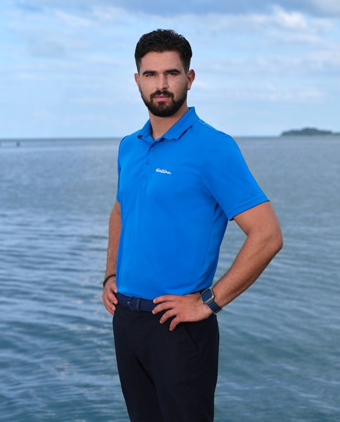 Johnny Arvanitis wearing a blue polo in front of water