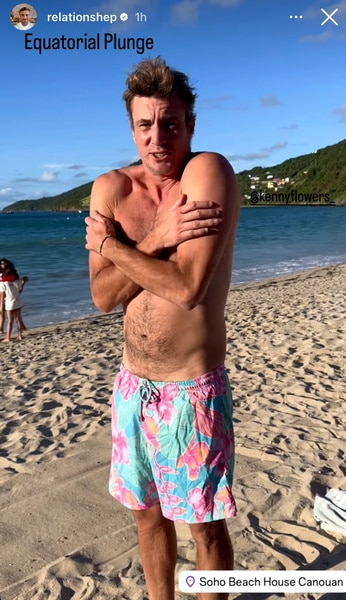 Shep Rose wearing swim trunks, hugging himself before jumping in the ocean.