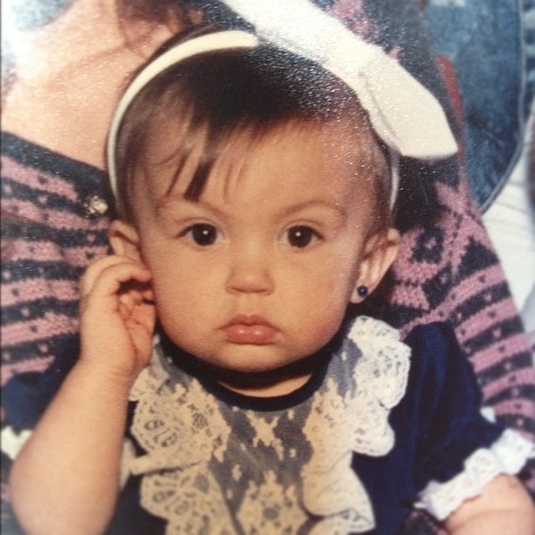 Ashlee Holmes as a baby wearing a large bow headband