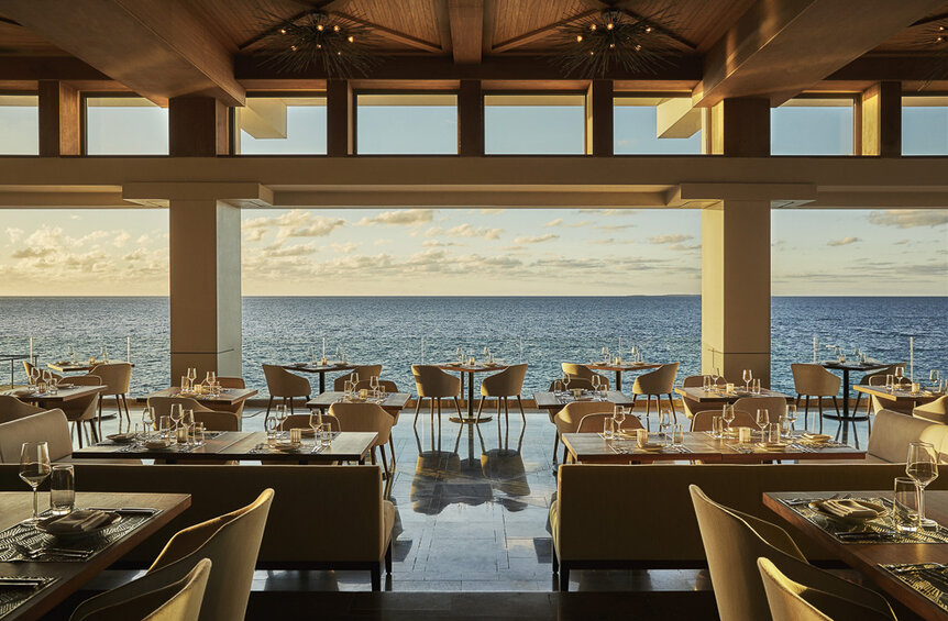 A restaurant with seating overlooking a sunset on the ocean.