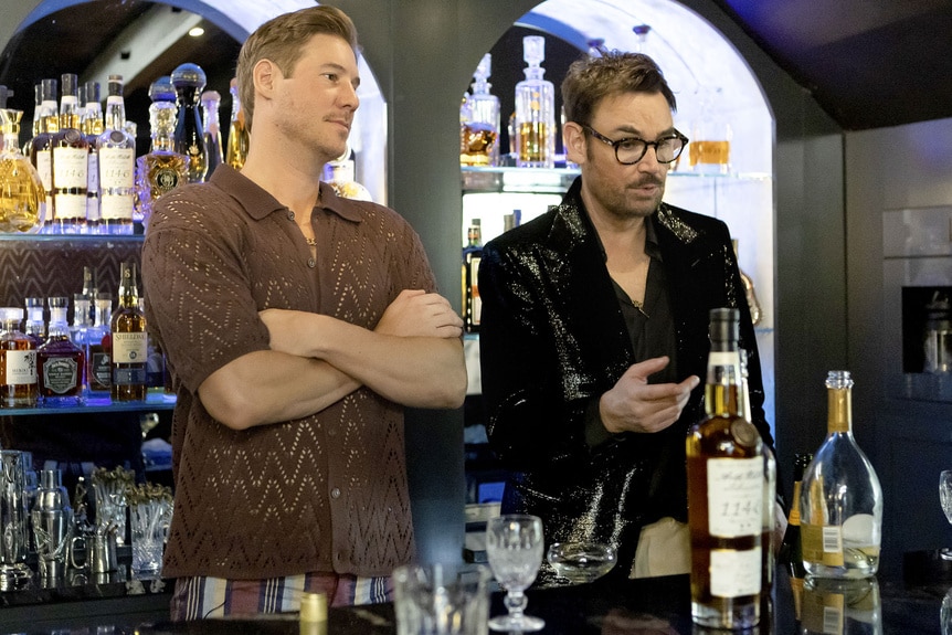 Austen Kroll and Whitney Sudler-Smith talk while standing at a bar.