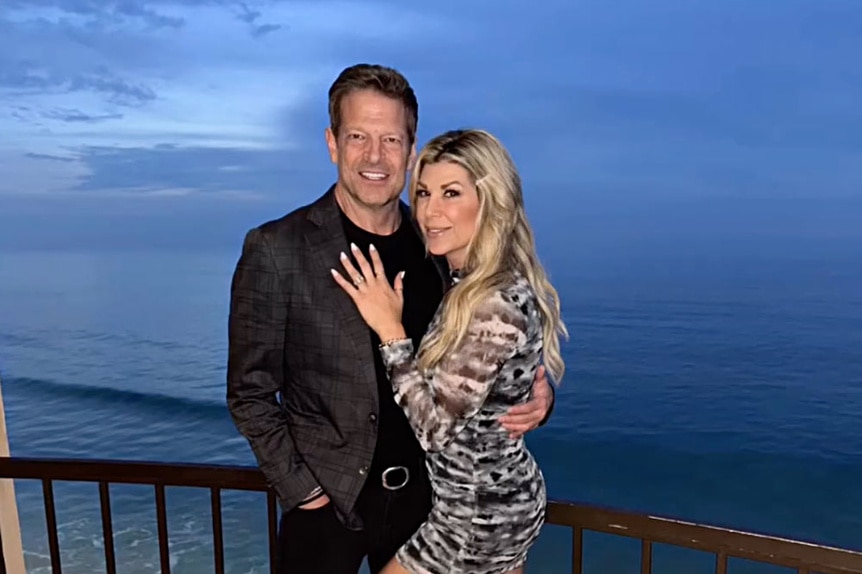 Alexix Bellino and John Janssen together on a balcony overlooking water.