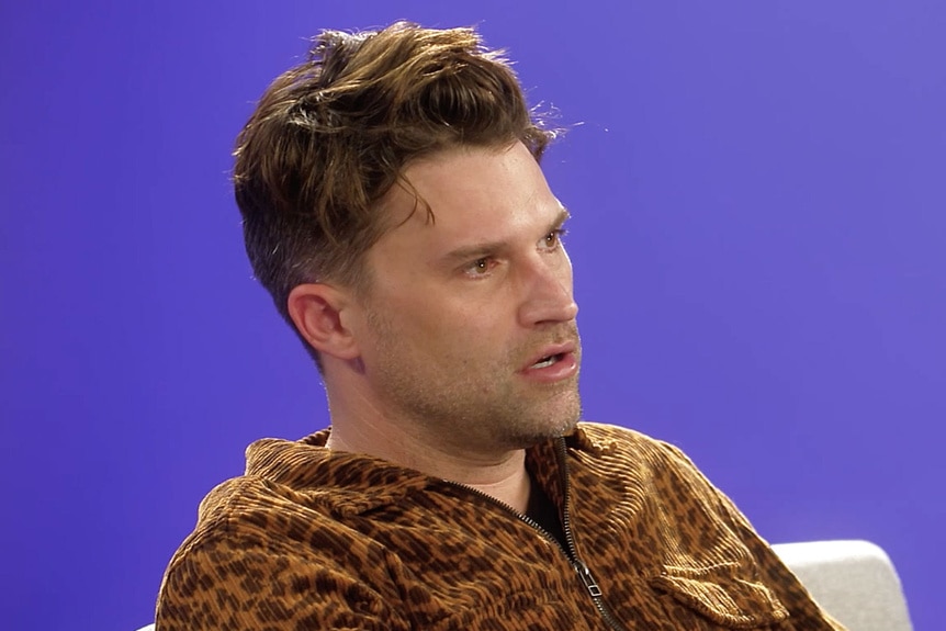 Tom Schwartz talking in front of a purple backdrop.