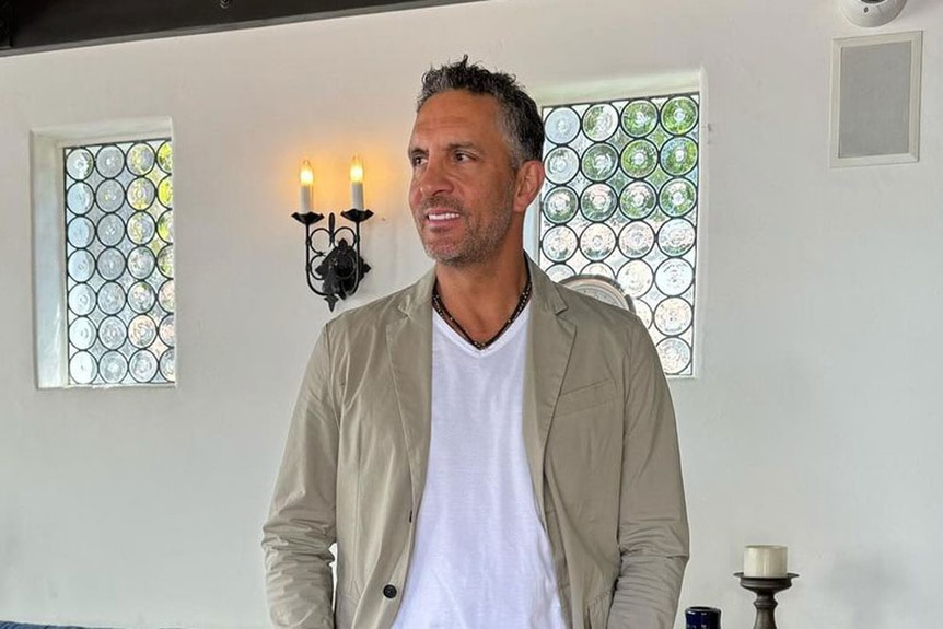 Mauricio Umansky wearing a beige jacket and white tee in a livingroom.