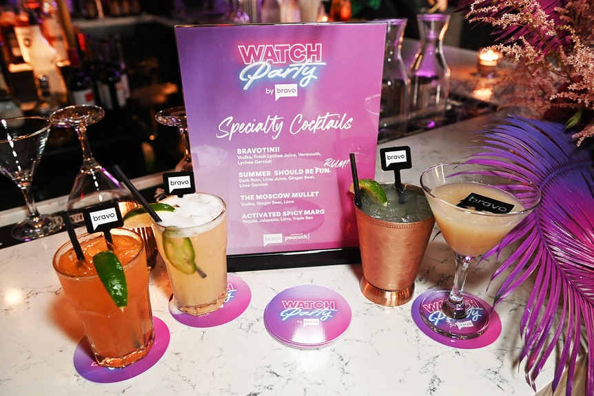 Cocktails surrounding a drink menu on a countertop.