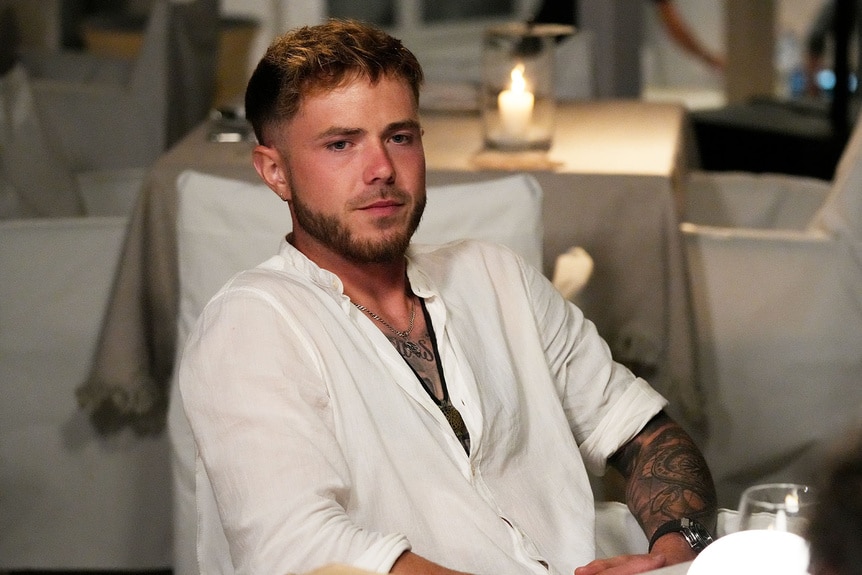 Nathan Gallagher sitting at a dining table in a white shirt.