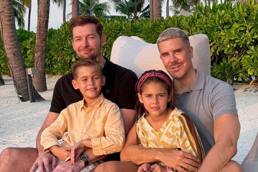 Fredrik Eklund on a beach with his husband and two young children.