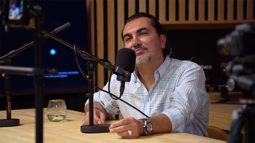 Bill Aydin sitting at a table recording a video.