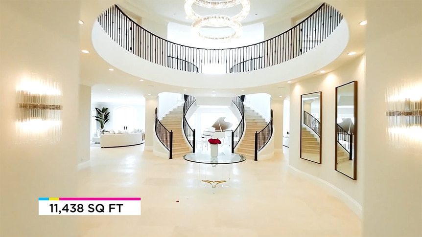 The foyer of Josh Altman's listing featuring a double staircase and chandelier.