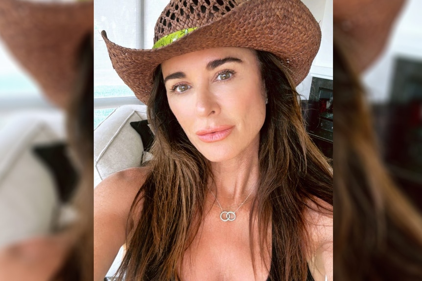 Kyle Richards wearing a cowboy hat and a black bathing suit/