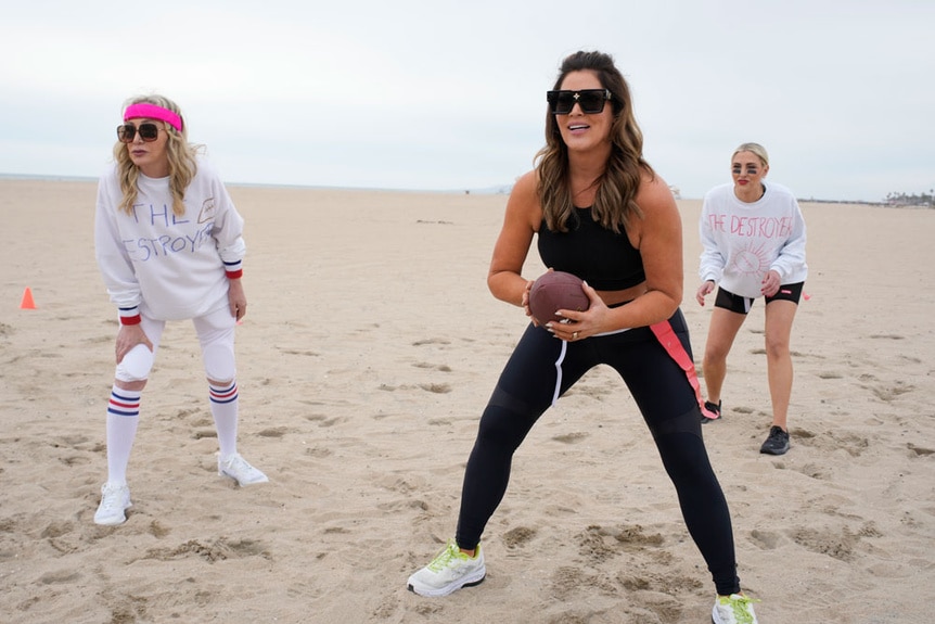 Emily Simpson, Shannon Beador and Gina Kirschenheiter playing flag football on a beach