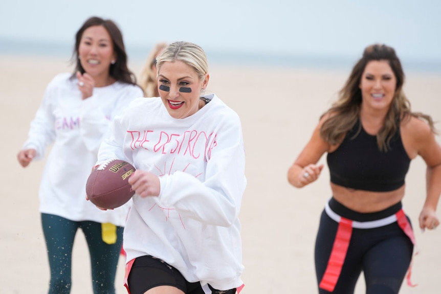 Emily Simpson, Katie Ginella and Gina Kirschenheiter playing flag football on a beach