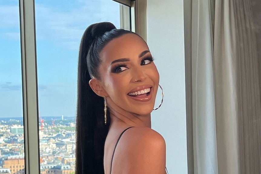 Scheana Shay smiling and posing in front of a window.