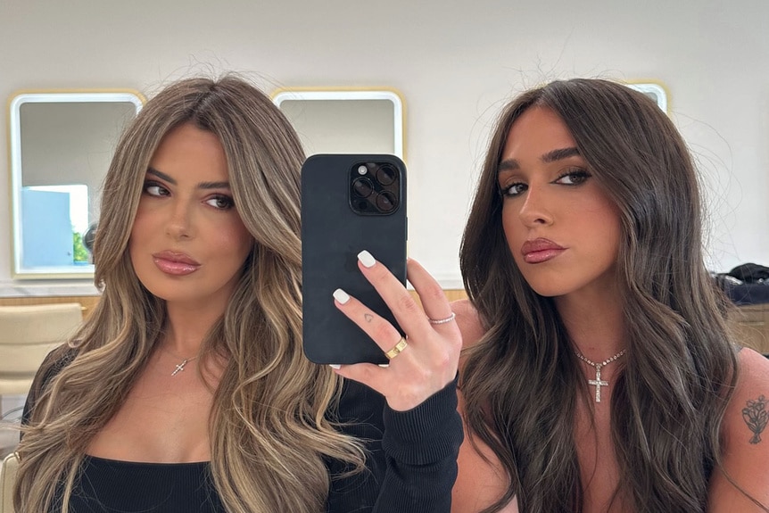 Brielle Biermann and Ariana Biermann pose together in a mirror.