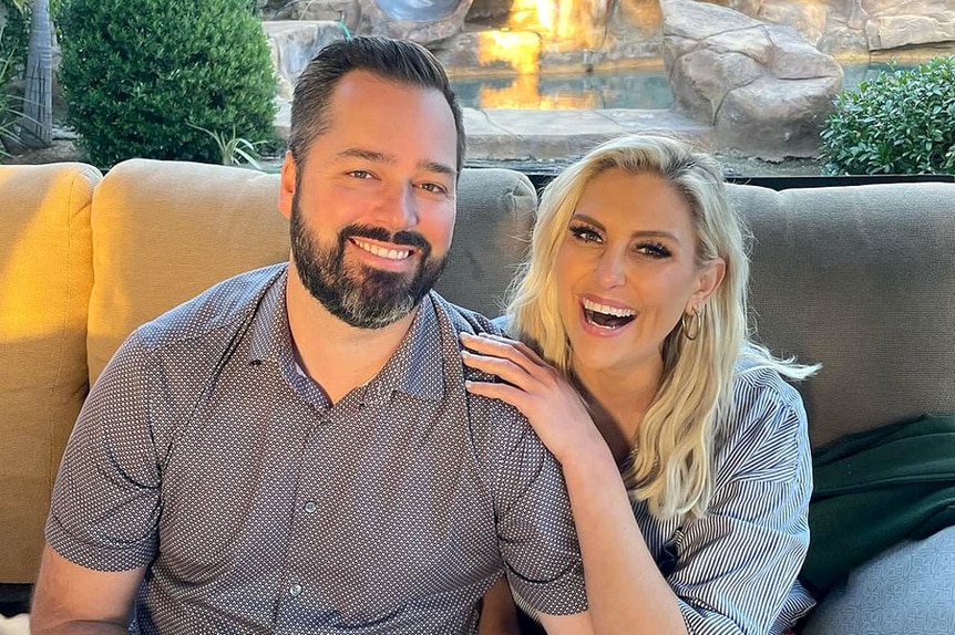 Gina Kirschenheiter and Travis Mullen sitting outside on a couch together.