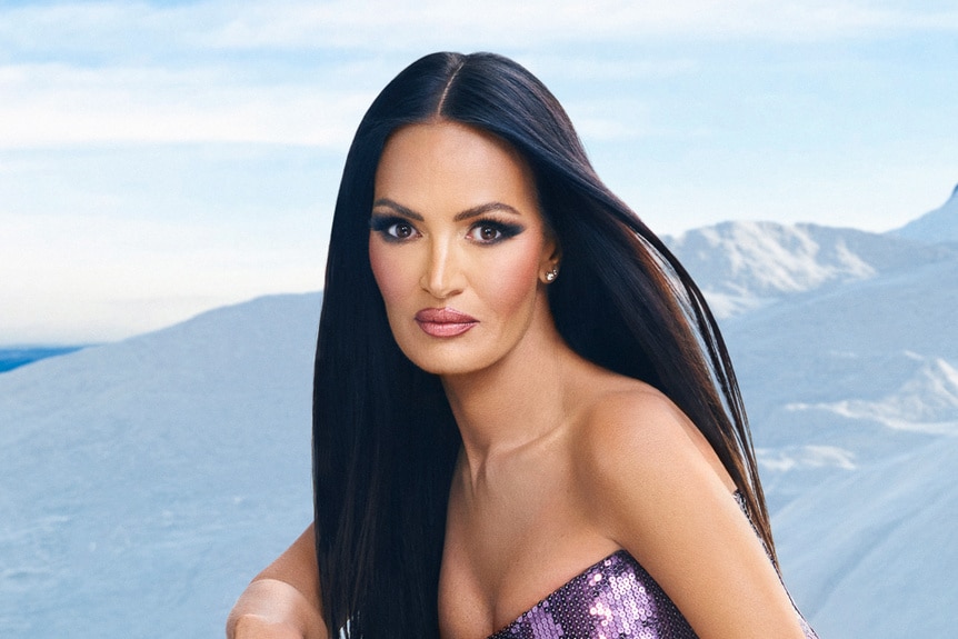 Lisa Barlow wearing a purple gown and standy in front of a snowy mountain