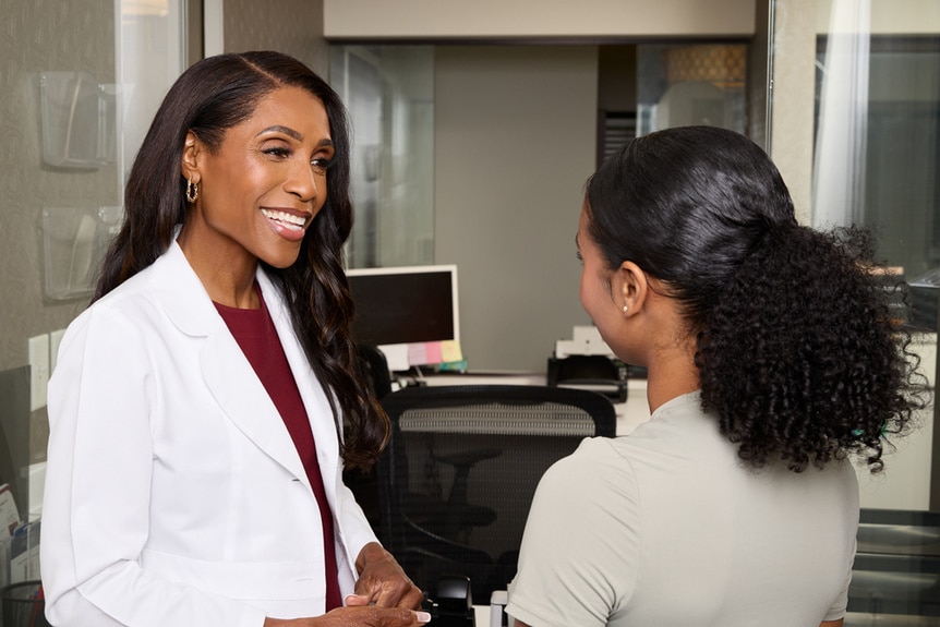 Dr. Jackie Walters talks and smiles with a patient in an office.