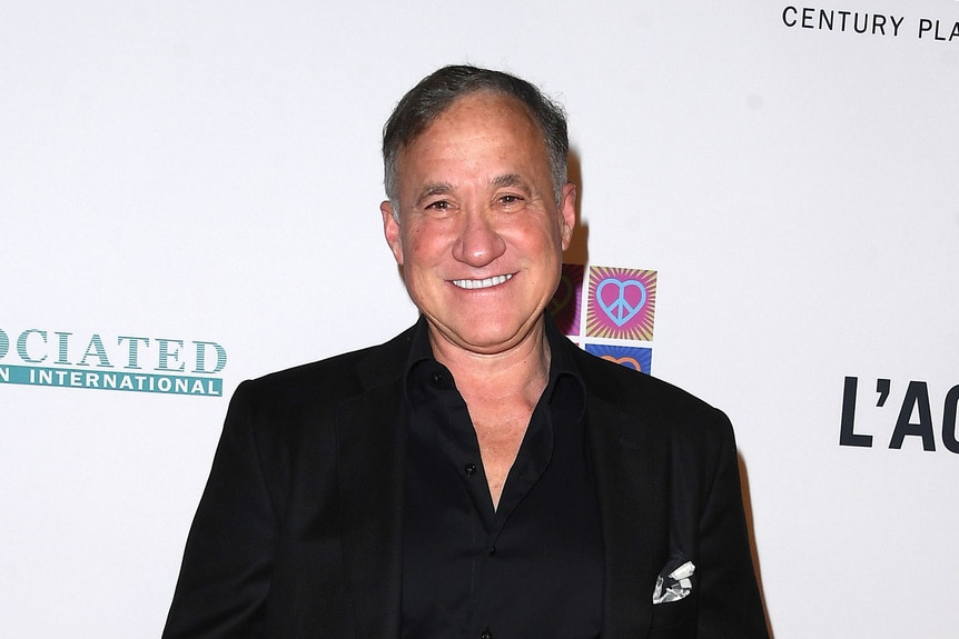 Dr. Terry Dubrow smiling in front of a step and repeat.