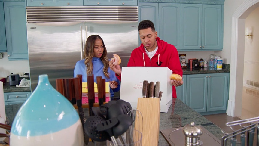 Mary Cosby and Robert Cosby Jr. eating donuts in their kitchen.