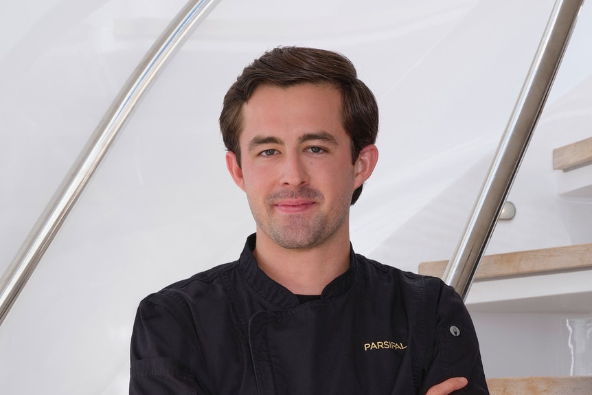 Cloyce Martin posing in uniform onboard the Parsifal 3 in front of a marina.