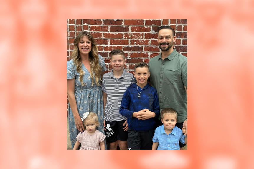 Briana Culberson posing with her family in front of a brick wall.