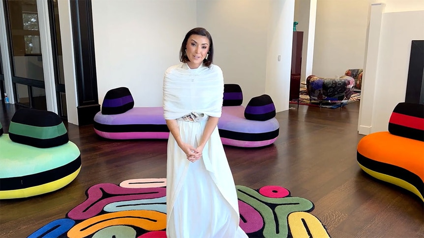 Bronwyn Newport smiling while standing in front of colorful sofas in her home.