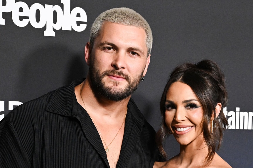 Scheana Shay and Brock Davies posing together in front of a step and repeat at an event.