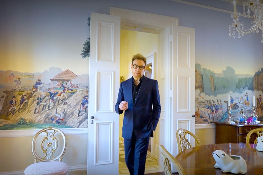 Whitney Sudler-Smith in his dining room with hand painted wallpaper.