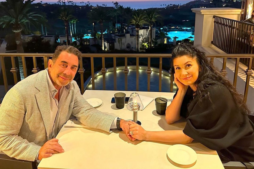 Paul Nassif holding his wife's hand at dinner.