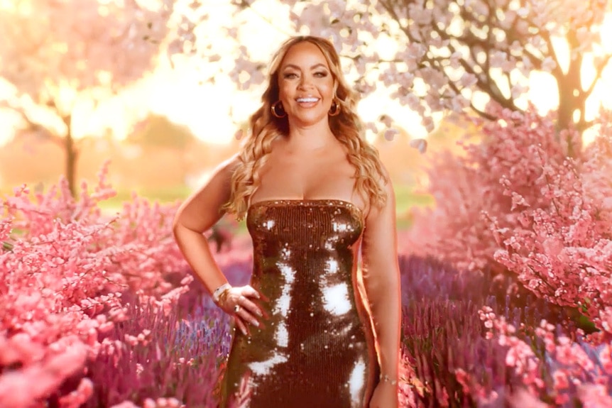 Gizelle Bryant wearing a sequin gold dress in front of cherry blossom trees