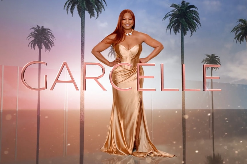 Garcelle Beauvais wearing a gold gown with her first name written across her