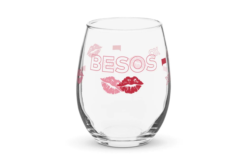 A stemless wine glass with Besos written on it and two lip icons