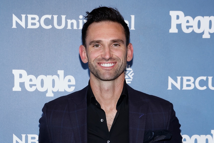 Carl Radke smiles in a black shirt on the red carpet for the People and NBCUniversal Upfront Party