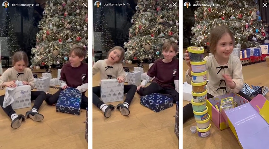 Phoeni and Jagger Kemsley opening Christmas gifts by the tree.