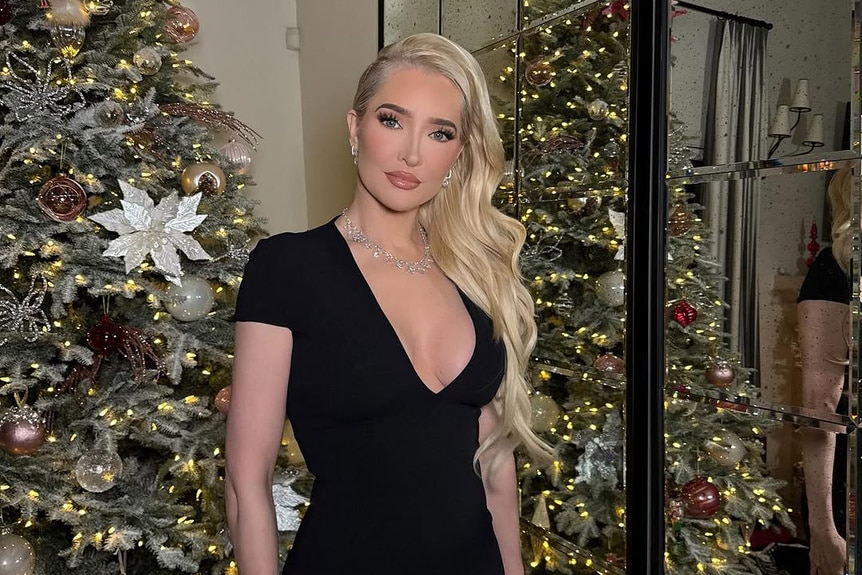 Erika Jayne wearing a black dress standing in front of a Christmas tree